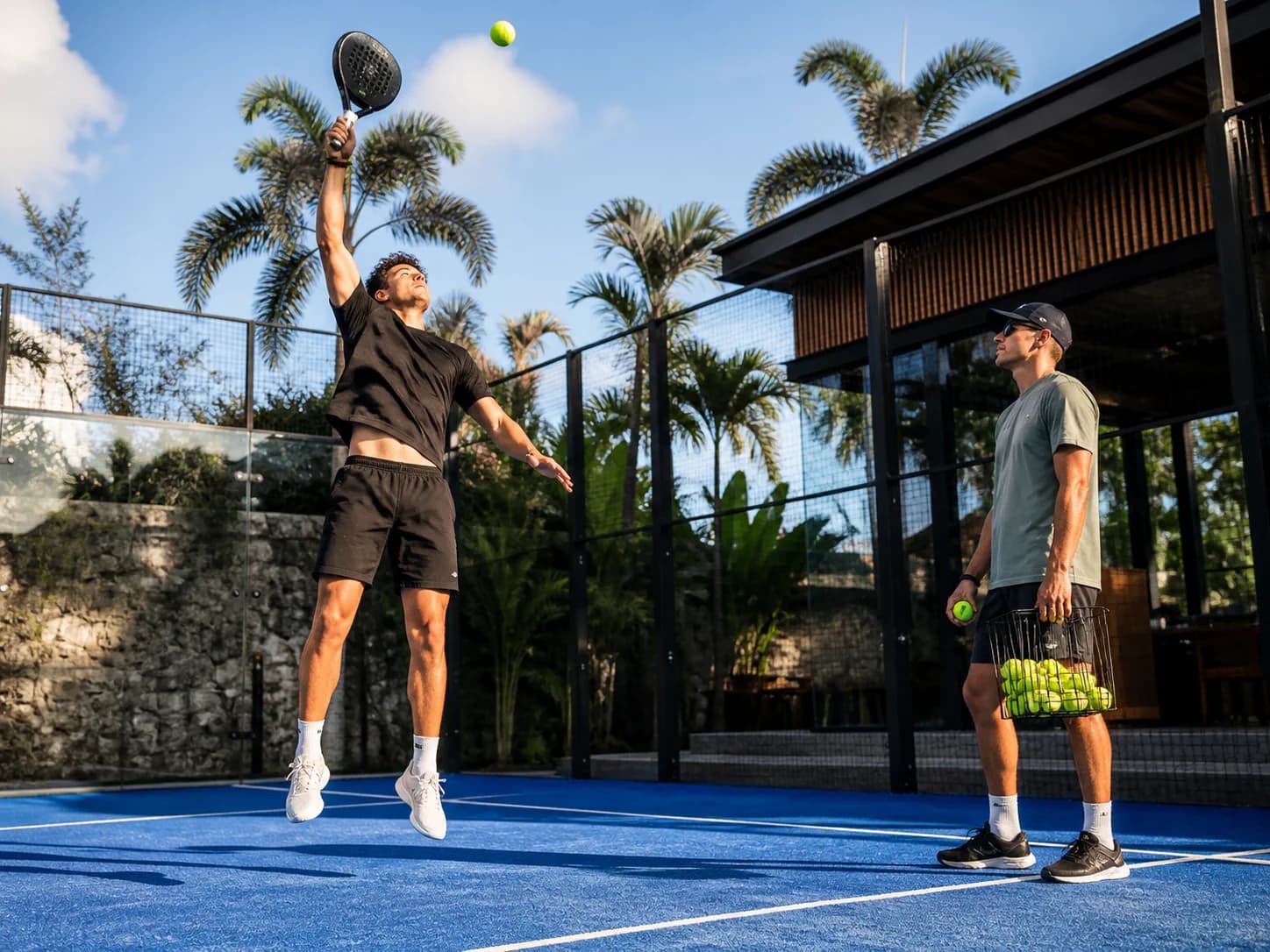 Advanced player practising an overhead smash with a coach